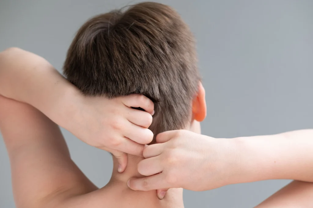 Kind fasst sich wegen Beschwerden an den Nacken